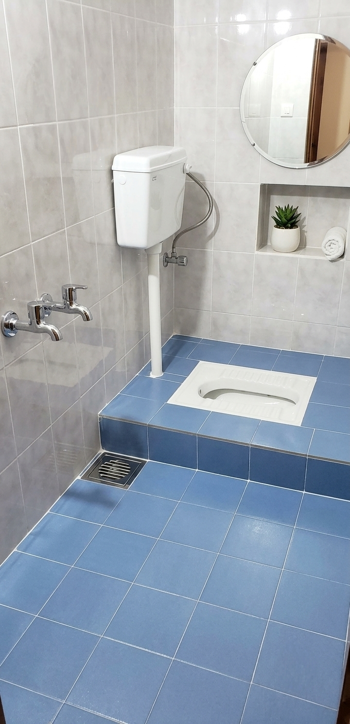 Spotless bathroom with blue floor tiles, grey wall tiles and a round mirror